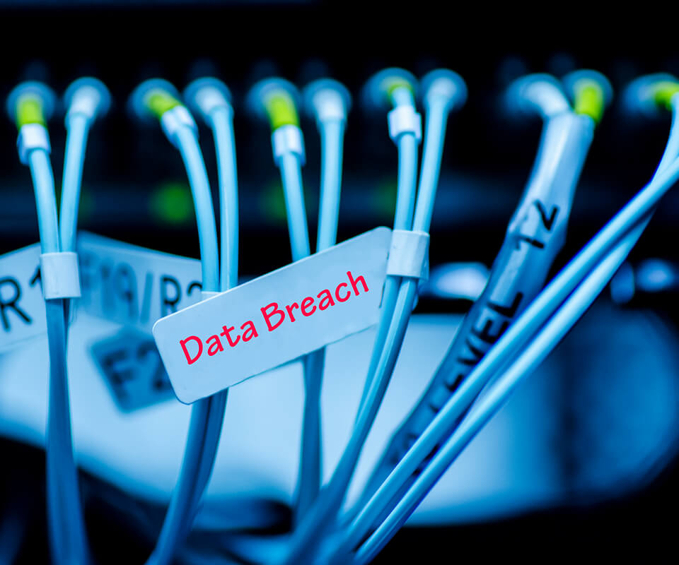 A closeup of 12 cables plugged into a board. One of them has a tag that reads “Data Breach” in red letters.