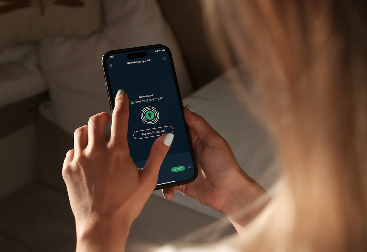 We are looking over the shoulder of a blond woman who is connecting to Newshosting’s VPN on her cellphone.