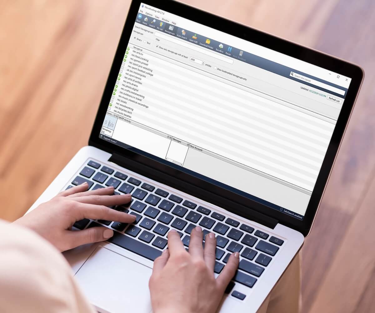 Closeup of a pair of hands typing on a laptop that shows the Newshosting newsreader's Newsgroup search feature.