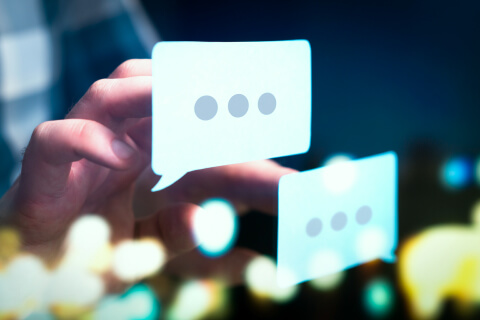 Closeup of a pair of hands pressing on two chat bubble icons floating in mid-air.